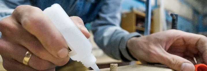 Person trägt Klebstoff auf Holz auf